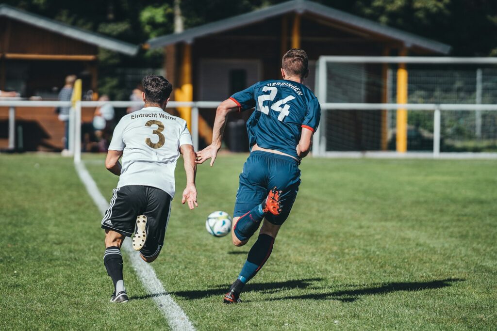 Twee voetballers springen tegen elkaar op in een kopduel