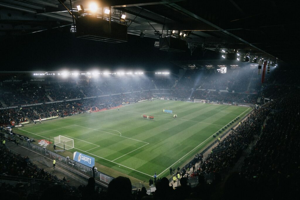 Verlicht voetbalstadion op een avond, gezien vanaf de tribune
