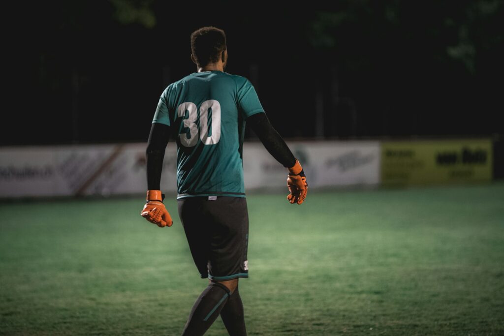 Keepershandschoenen op het gras voor een doel in een voetbalstadion