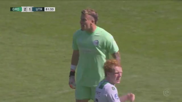 De doelman van FC Groningen in een lichtgroen keepersshirt schreeuwt aanwijzingen tijdens een thuiswedstrijd in Euroborg